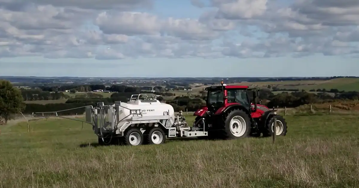 Tractor and Tow and Fert machine parked in a hilltop paddock, with farmland visible in the distance.